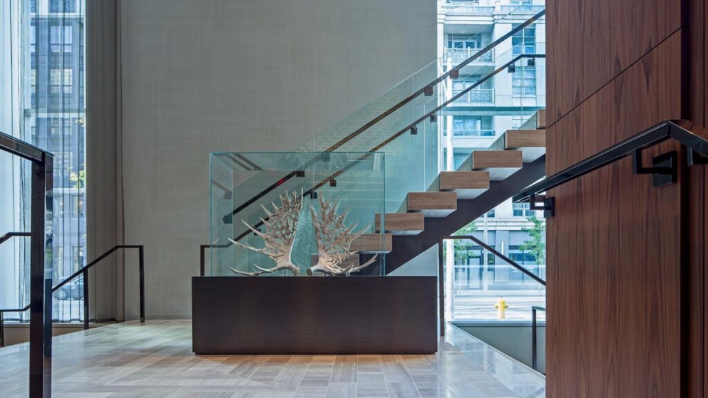 Interior commercial staircase with glass railing and panels requiring precise fabrication for proper fit and alignment