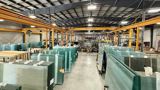BG Glass Technologies commercial glass fabrication facility with large architectural glass panels and overhead crane systems in Ontario warehouse.